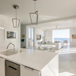 Your sleek modern kitchen flows seamlessly into the bright living area, where panoramic sea views create the perfect backdrop for your coastal getaway.