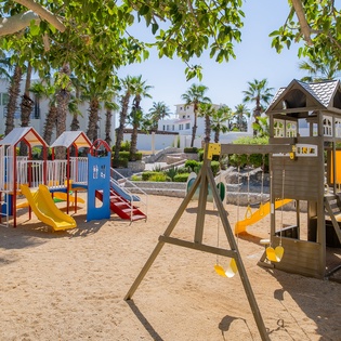 Let your little ones explore and play safely in this colorful playground, complete with slides, swings, and climbing structures surrounded by tropical palms.