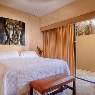 Drift off under crisp white linens in your serene bedroom, where warm earth tones and artistic accents create a peaceful retreat. Step through sliding glass doors to your private outdoor space.