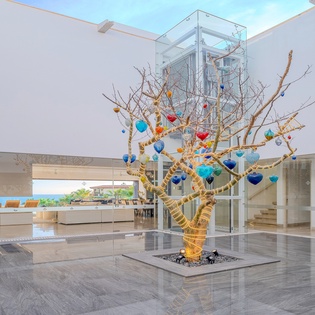 You'll be captivated by this stunning open-concept space featuring a dramatic art tree centerpiece beneath soaring glass ceilings that flood the area with natural light.