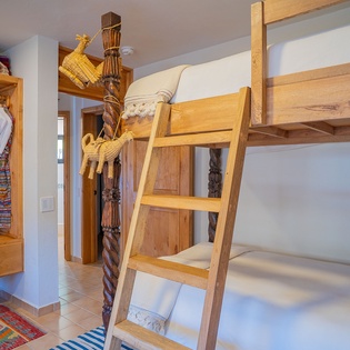Rest in your charming bunk bed room featuring handcrafted wooden furniture and colorful textiles that bring warmth to your mountain getaway.