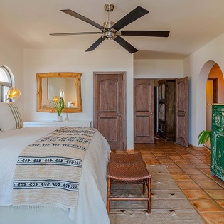 Sink into crisp linens and admire the terracotta floors, rustic wood doors, and vibrant green antique dresser that give your bedroom authentic Southwestern character.