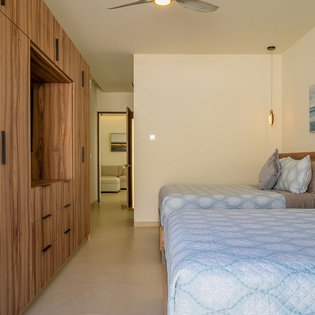 Rest peacefully in this modern twin bedroom featuring warm wood accents, built-in storage, and gentle pendant lighting.