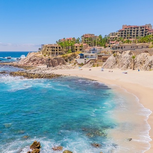 Beautiful coastal resort area with pristine sandy beach and crystal-clear turquoise waters surrounded by luxury accommodations.