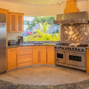 Your gourmet kitchen awaits with professional-grade appliances, granite counters, and tropical garden views through the window.