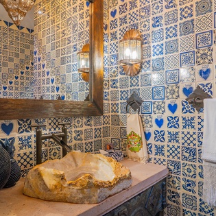 Step into your private bathroom featuring stunning blue Portuguese tiles and rustic stone sink that transforms daily routines into moments of pure delight.