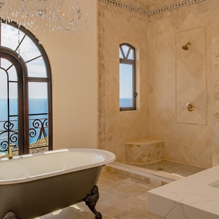 En suite bathroom with bathtub, walk-in shower, and ocean views