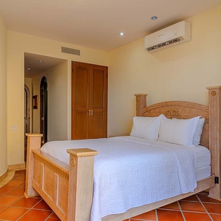 Sink into crisp white linens on this handcrafted bed, where carved wood details and terracotta floors bring warmth to your personal retreat.