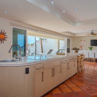 Enjoy your morning coffee in this bright open-plan space featuring a sleek modern kitchen with terracotta tile flooring flowing into a comfortable dining area.