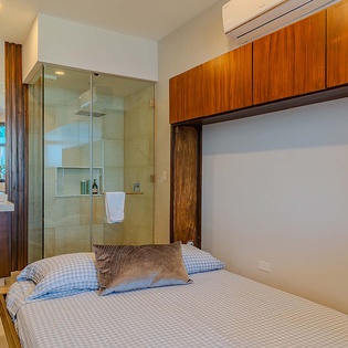 Your bedroom combines comfort and convenience with a beautiful glass-enclosed shower, warm wood cabinetry, and climate-controlled air conditioning for ultimate relaxation.