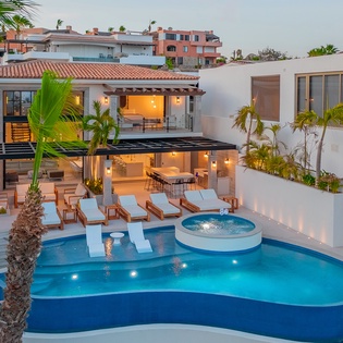 Modern luxury villa features stunning pool area with hot tub, perfect for evening relaxation under tropical palms.