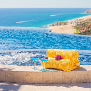 Sink into luxury at your infinity pool where yellow towels and cocktails await your perfect seaside escape.
