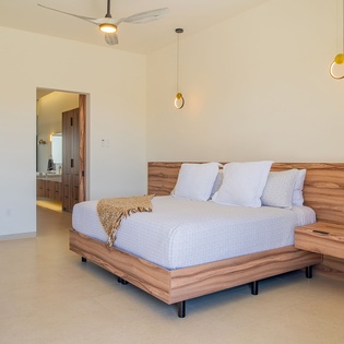 Sink into your modern sanctuary with its sleek platform bed, warm wood accents, and stylish pendant lighting creating perfect ambiance.