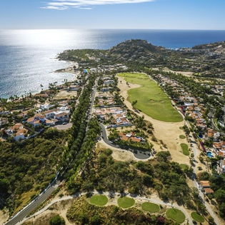 Spectacular aerial view showcases the coastal community with championship golf course, pristine beaches, and hillside homes overlooking the sparkling Mediterranean coastline.