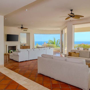 Unwind in your spacious living room where ocean breezes flow freely through open glass doors, framing stunning sea views that stretch to the horizon.