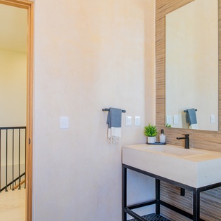 Your stylish bathroom features a sleek vanity, warm wood textures, and plush towels ready for your arrival.