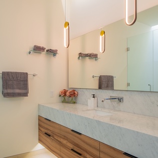 Unwind in your sleek modern bathroom with marble countertops, warm wood vanity, and luxurious towels waiting for you.