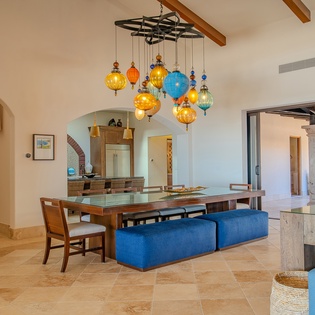 Relax in your stunning open-plan living space where colorful pendant lights dance above, blue seating invites conversation, and archways frame the perfect vacation atmosphere.
