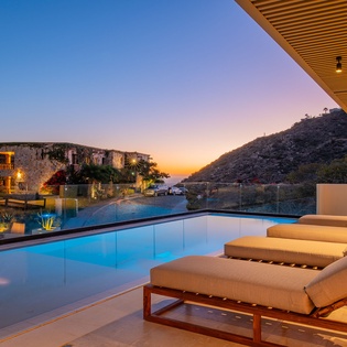 Stunning twilight views from this infinity pool terrace overlooking dramatic desert hills and illuminated stone architecture.
