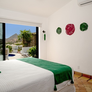 Wake up to stunning mountain and pool views from your bright bedroom, where vibrant artwork creates a cheerful atmosphere.