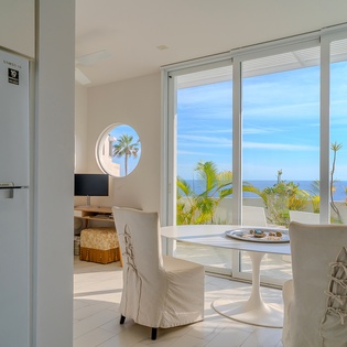 Dine with stunning ocean views through floor-to-ceiling windows, where tropical palms frame your perfect beachside breakfast spot.