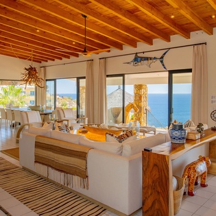 Unwind in your open-concept living space where exposed beam ceilings meet stunning ocean views through floor-to-ceiling windows.