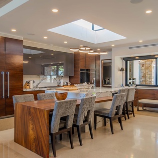 Gather around this stunning wood dining table under a skylight, where natural light streams in and every meal feels special with the gourmet kitchen close at hand.
