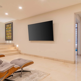 Settle into the iconic lounge chair and unwind in your spacious living area, complete with wall-mounted TV and clean, modern design for ultimate relaxation.