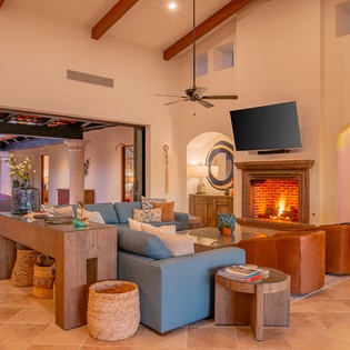 Unwind in your spacious living room where rustic beams meet modern comfort, complete with a crackling fireplace for cozy evenings together.