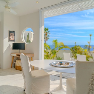 Your elegant dining space opens seamlessly to tropical paradise, where stunning ocean views and swaying palms create the perfect backdrop for memorable meals.