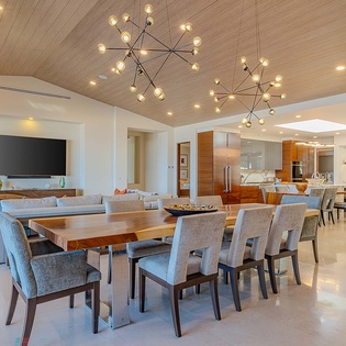 You'll love gathering around this spacious dining table beneath stunning statement chandeliers, with the sleek open kitchen and cozy living area just steps away—perfect for entertaining or relaxing together.