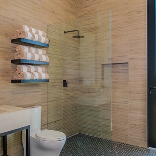 Indulge in your private spa-like bathroom with sleek glass shower, warm wood accents, and refreshing sea views.