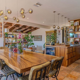 Gather around the stunning live-edge wood table where meals become memories beneath artisan lighting and vibrant greenery. The open, airy design blends seamlessly with the fully-stocked bar and kitchen, creating your perfect space for connection and celebr