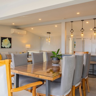 Your open-plan living flows seamlessly from cozy seating to elegant dining, all warmed by modern pendant lighting.