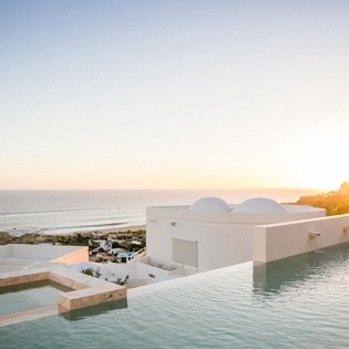 Stunning infinity pools cascade toward the ocean at golden hour, creating a serene Mediterranean paradise.