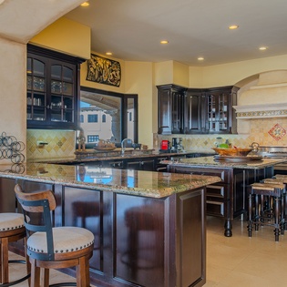 Gather around this magnificent kitchen island where culinary adventures await, featuring rich dark cabinetry and granite countertops perfect for cooking together.
