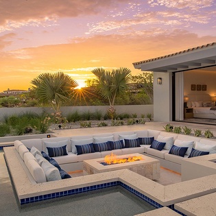 Stunning desert property surrounded by palm trees and native landscaping, offering a tranquil retreat with desert views as the sun sets over the horizon.
