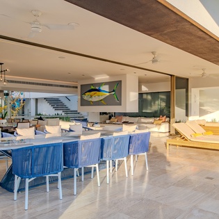 Your expansive outdoor terrace blends seamlessly with indoor comfort, featuring stylish blue dining chairs and lounge seating perfect for entertaining.