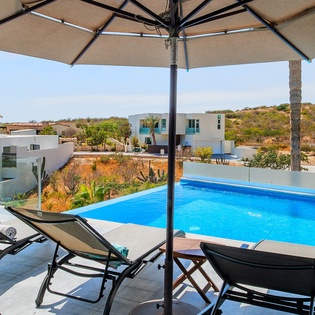 Relax by your private pool under a shaded umbrella, soaking up stunning views of the surrounding landscape and distant hills.