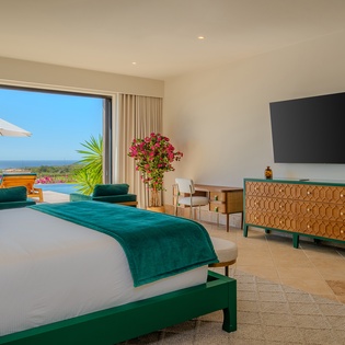 Wake up to stunning ocean views from your private retreat, where emerald accents and warm wood furnishings create perfect harmony with the endless blue horizon.