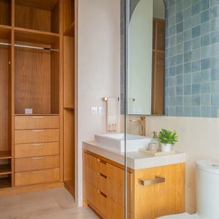 Your ensuite bathroom features elegant blue tiles and custom wood storage, with a spacious wardrobe for all your belongings.