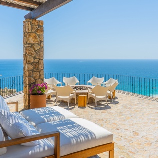 Stunning oceanfront terrace with panoramic sea views, comfortable loungers, and elegant outdoor dining perfect for seaside relaxation.