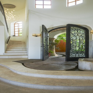 Step into your elegant entrance with soaring ceilings, curved staircases, and ornate ironwork that welcomes you to luxurious Mediterranean-style living.