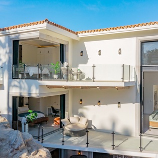 Modern luxury villa with striking multi-level terraces and panoramic glass walls showcasing contemporary Mediterranean architecture.