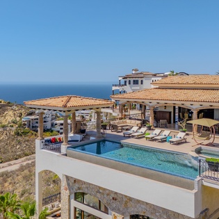 Luxurious hillside villa with rooftop pool overlooking the ocean and surrounding coastal community.