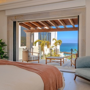 Wake up to stunning ocean views through expansive windows. Your private terrace beckons with comfortable seating and endless blue horizons.