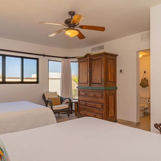 You'll rest easy in this peaceful bedroom with two comfortable beds, natural light from multiple windows, and a private ensuite. The ceiling fan keeps you cool while you enjoy the view.