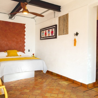 Unwind in your charming bedroom with vibrant Mexican touches, featuring a unique geometric headboard and colorful accents.