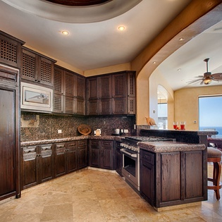 Cook with stunning ocean views from your fully equipped gourmet kitchen, featuring granite counters, rich wood cabinetry, and a breakfast bar perfect for casual dining.