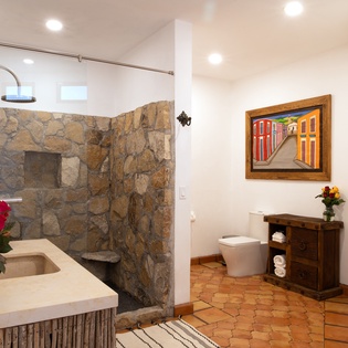 Step into your private spa-like bathroom featuring a stunning stone shower and elegant vanity with fresh flowers welcoming you.